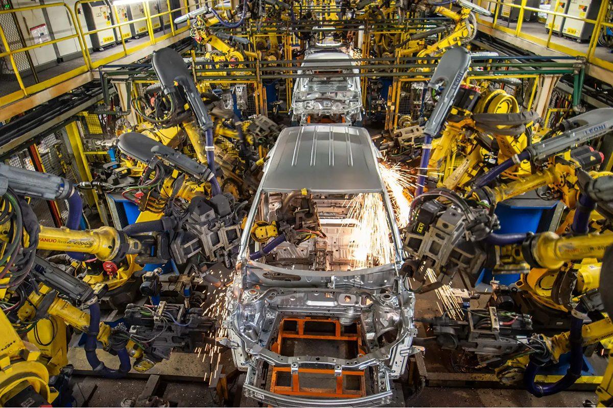 Vista de uma fábrica automotiva com máquinas operando com ar comprimido, destacando eficiência e precisão na linha de produção.
