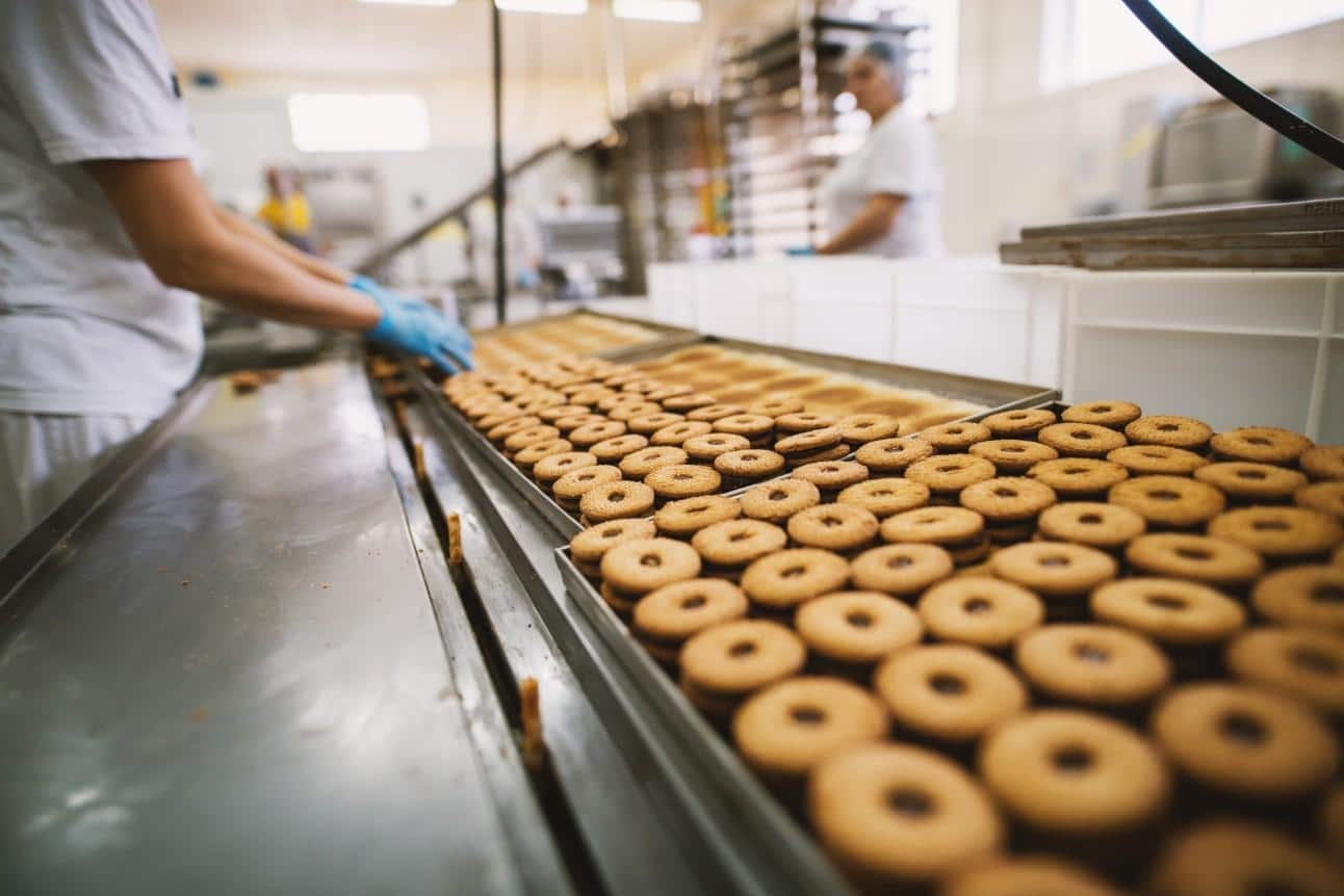 Funcionária operando em linha de produção de alimentos com suporte de chillers industriais, garantindo refrigeração eficiente e segurança alimentar.