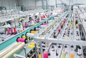 Fábrica têxtil com máquinas operando com ar comprimido, destacando a automação e eficiência no processo de produção de tecidos.