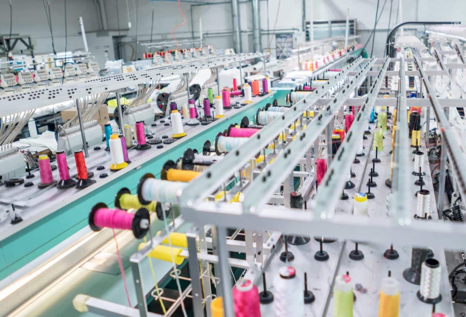 Fábrica têxtil com máquinas operando com ar comprimido, destacando a automação e eficiência no processo de produção de tecidos.